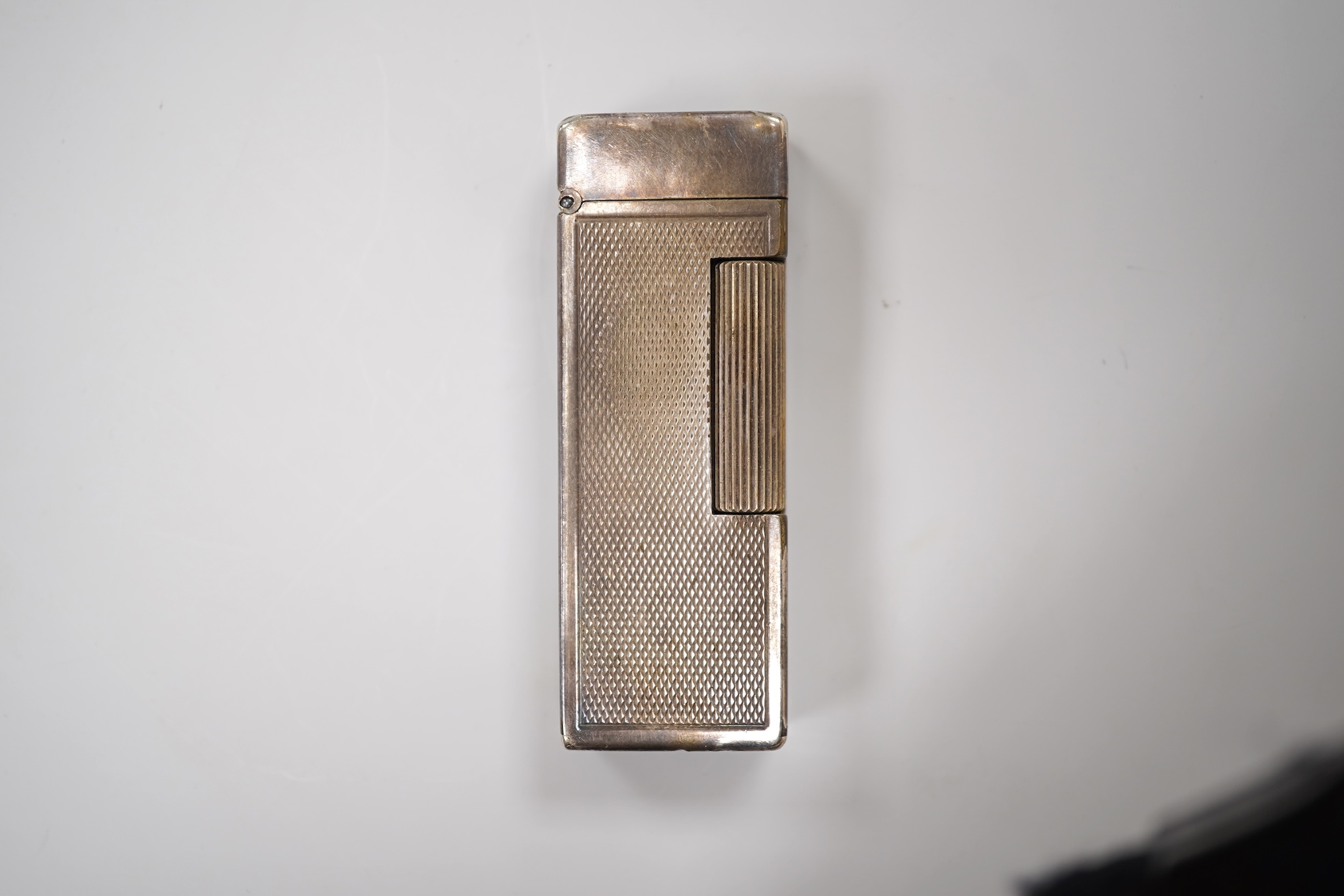 An early 20th century white metal oval locket, 40mm, on a silver chain, a silver plated Dunhill lighter, in Dunhill box, a white metal cased manual wind wrist watch and a tortoiseshell purse.